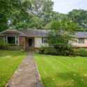 A split level home with green grass and a front walkway