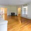 A living room with a white brick fireplace and a window with curtains